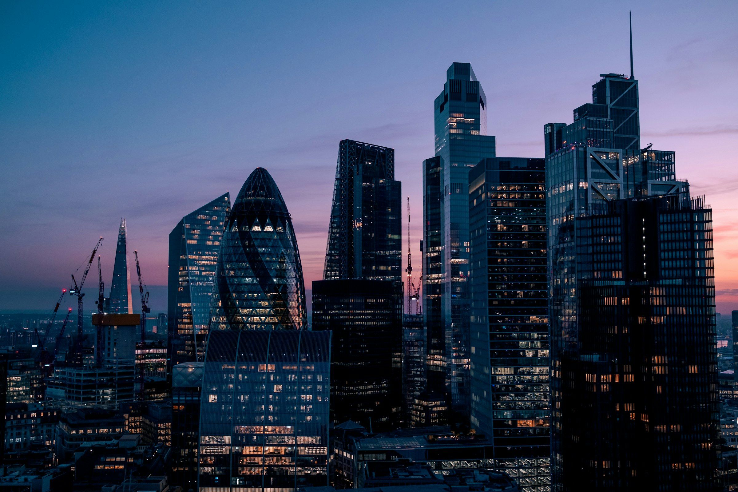 Glass skyscrapers of the City of London financial district against a violet dusk sky