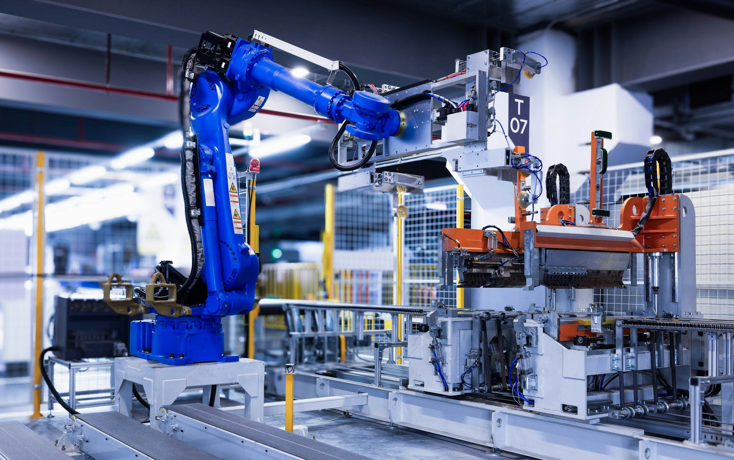Blue industrial robot arm working at an automated station on a factory production line